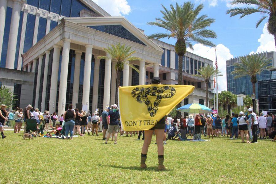 An anti-protester holds a “DON’T TREAD ON ME” flag during a rally for abortion rights in front of the Duval County Courthouse