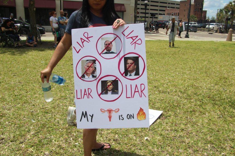 A protestor holds up a sign “The People’s Abortion Rally” for abortion rights in front of the Duval County Courthouse