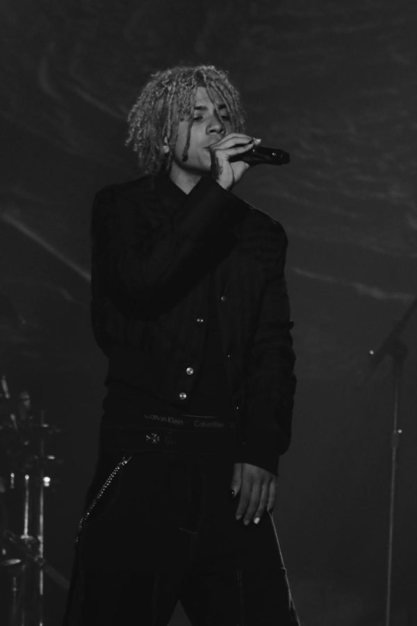 Iann Dior sings into a microphone and is wearing all black