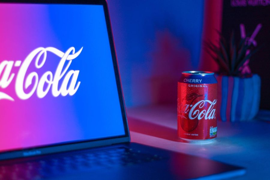 A can of cherry coke sits next to a laptop.