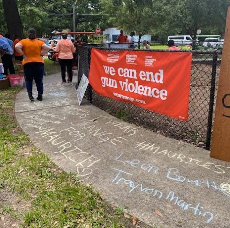 A Wear Orange banner reads we can end gun violence on a fence at Success Park during a clean-up event
