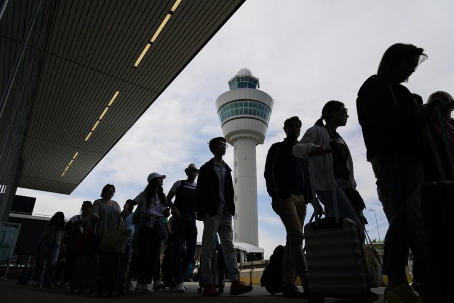 Travelers wait in long lines outside the terminal building to check in and board flights