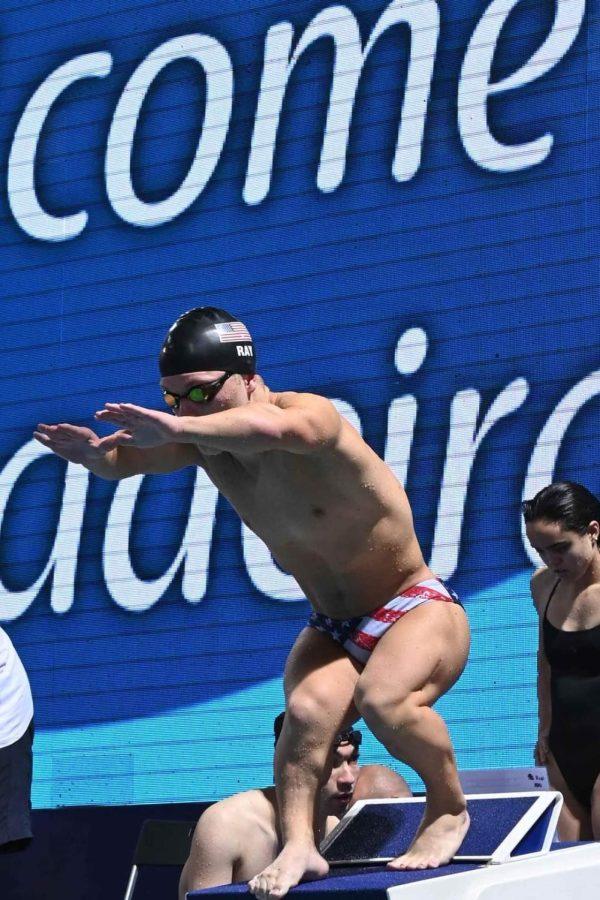 Wearing a black swim cap and goggles, Morgan Ray stands on a diving block