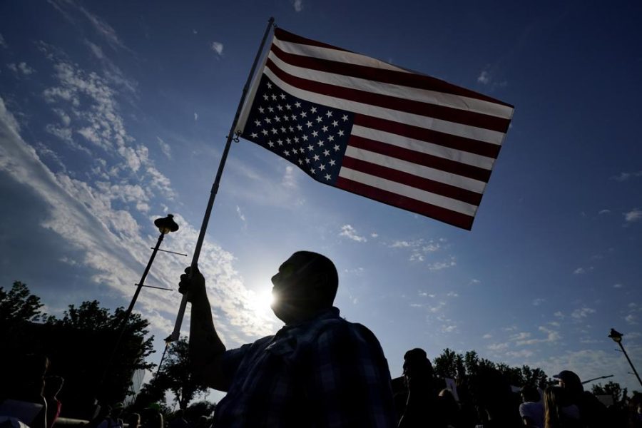 A protester holds an American flag on a flag pole