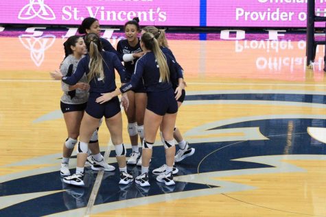 Group of volleyball players huddle together following a point.