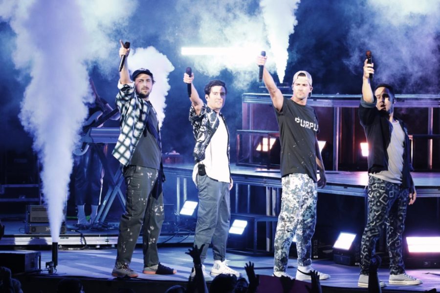 All four big time rush members raise their microphones up and out toward the camera