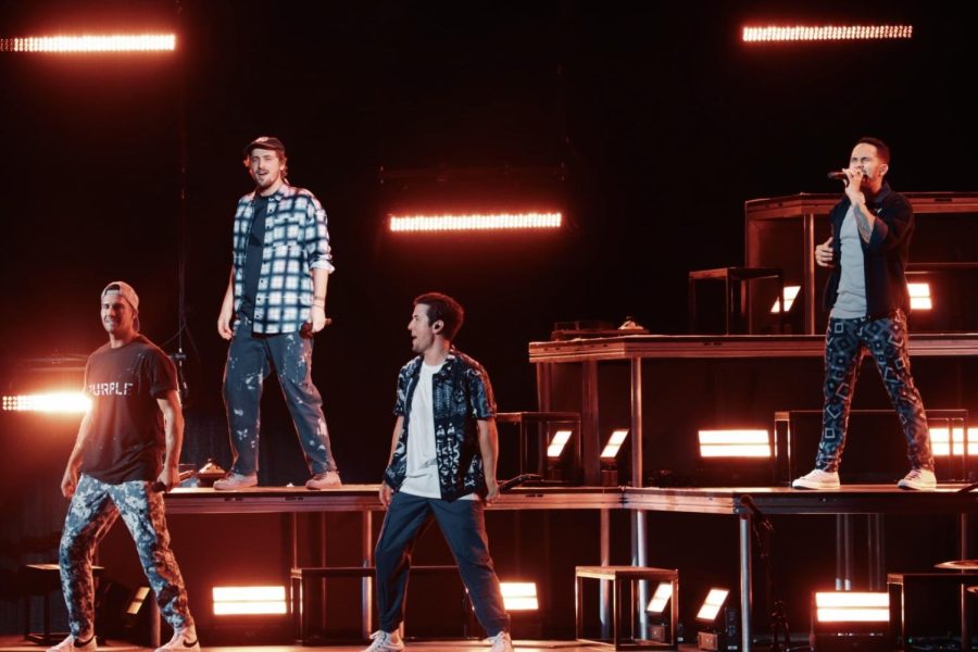 Big Time Rush members perform on a stage lit by red lights