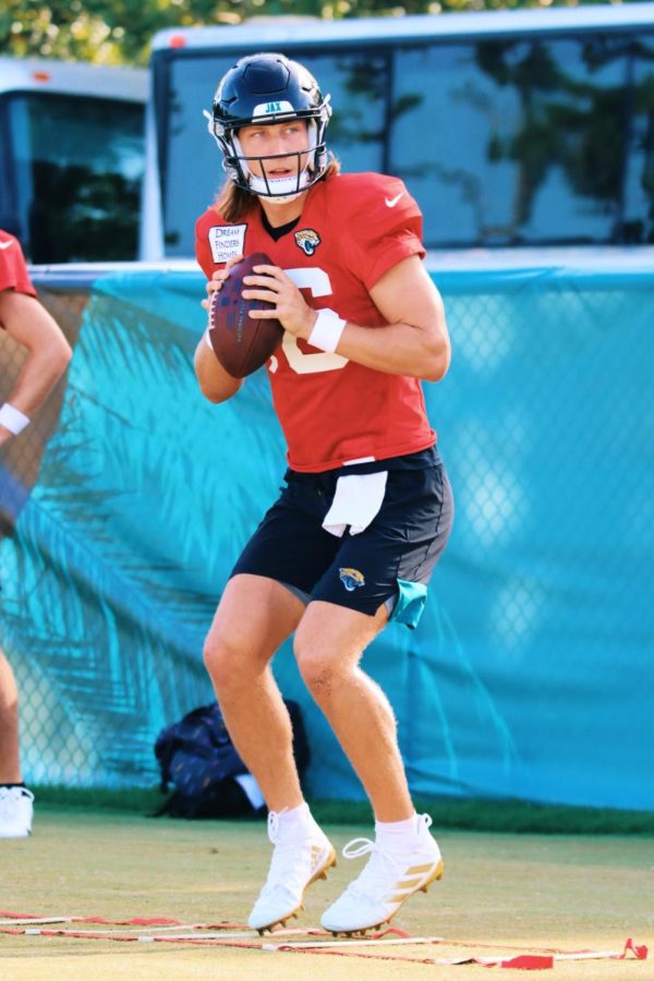 Trevor Lawrence gets ready to throw a football while wearing a red jersey