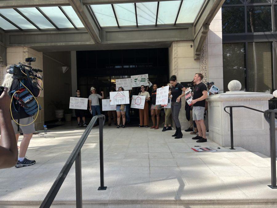 Activists hold up their fist, chanting, with large white signs