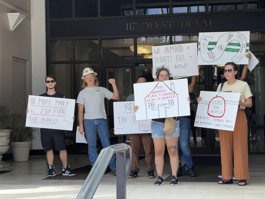 Activists hold up their fist, chanting, with large white signs