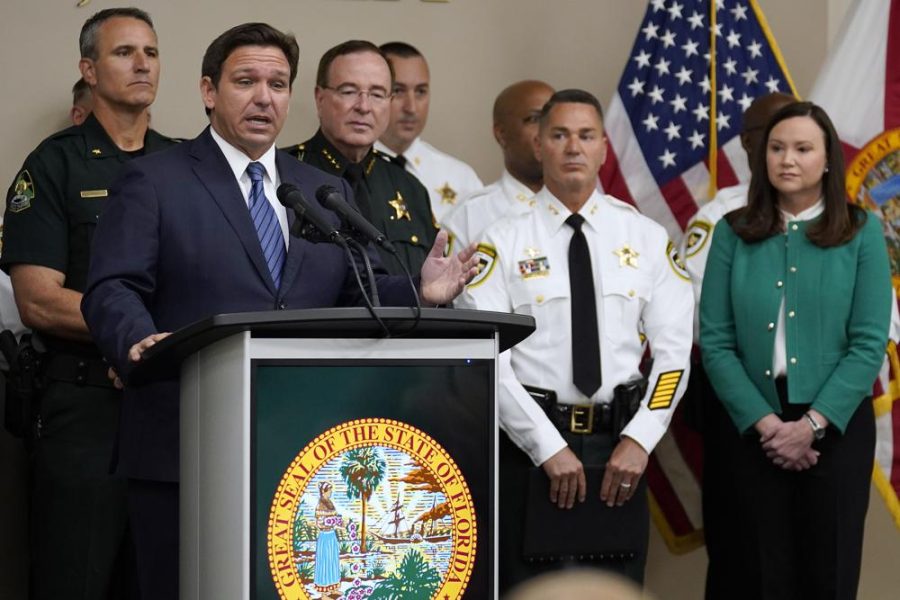 DeSantis talks at a podium, wearing a blue suit