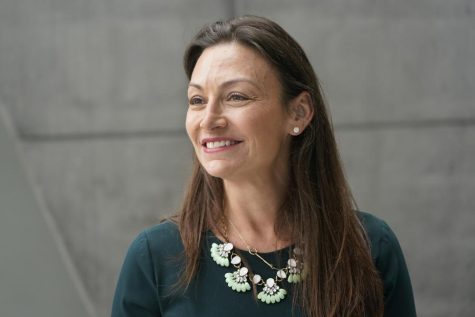 Nikki Fried smiles for a photo, wearing a white flowery necklace and green shirt