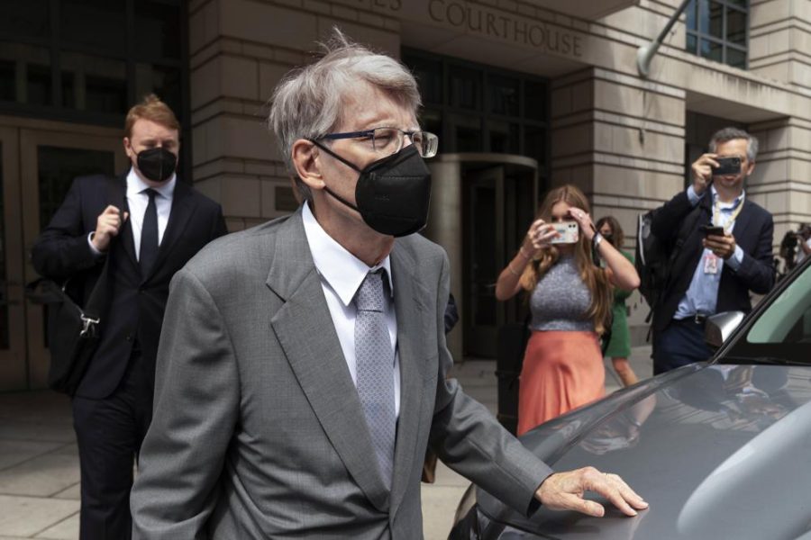 Stephen King, wearing an all grey suit and black mask, walks away from the courthouse toward a car out of frame