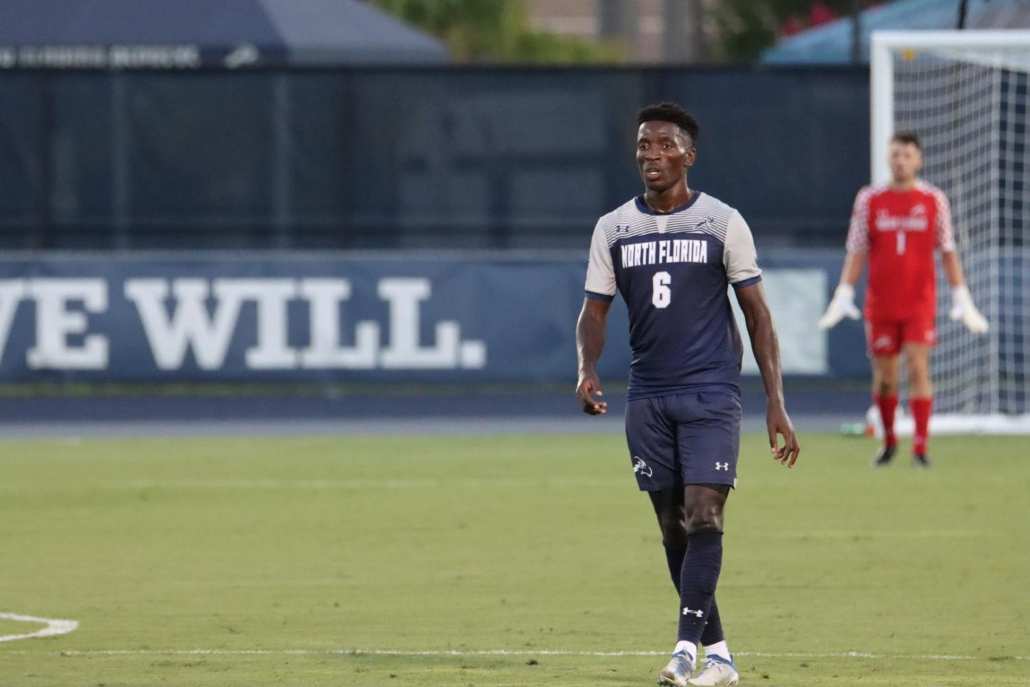 UNF player walks across the field, with goalkeeper in the background.