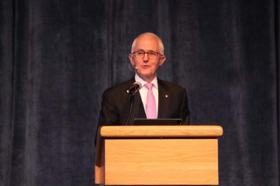 Malcolm Turnbull speaks behind a podium wearing a black suit and glasses