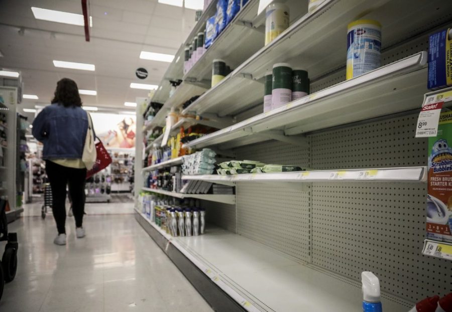 Sparsely stocked shelves with a woman walking past