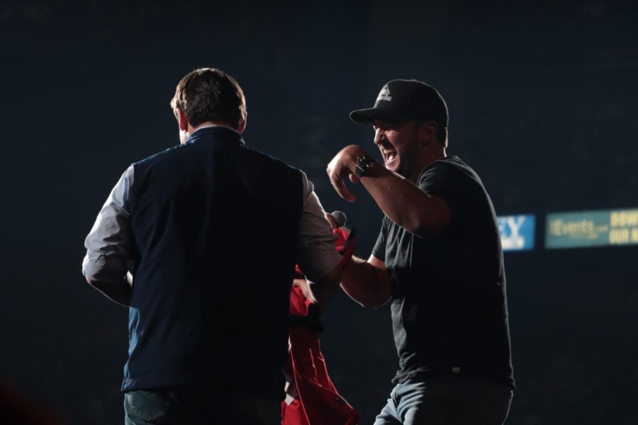 Luke Bryan laughs as he hands DeSantis a red jersey