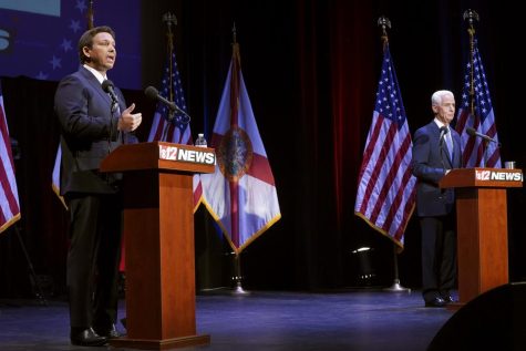 DeSantis and Crist stand behind their respective podiums during the debate