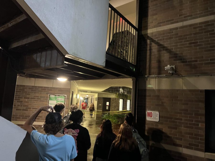 Students stand behind yellow caution tape