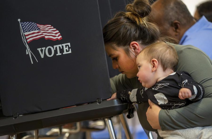 Miranda Padilla holds her 11-month-old son Grayson Sanchez while marking her ballot at a polling center in the South Valley area of Albuquerque, N.M., Tuesday, Nov. 8, 2022 (AP Photo/Andres Leighton)