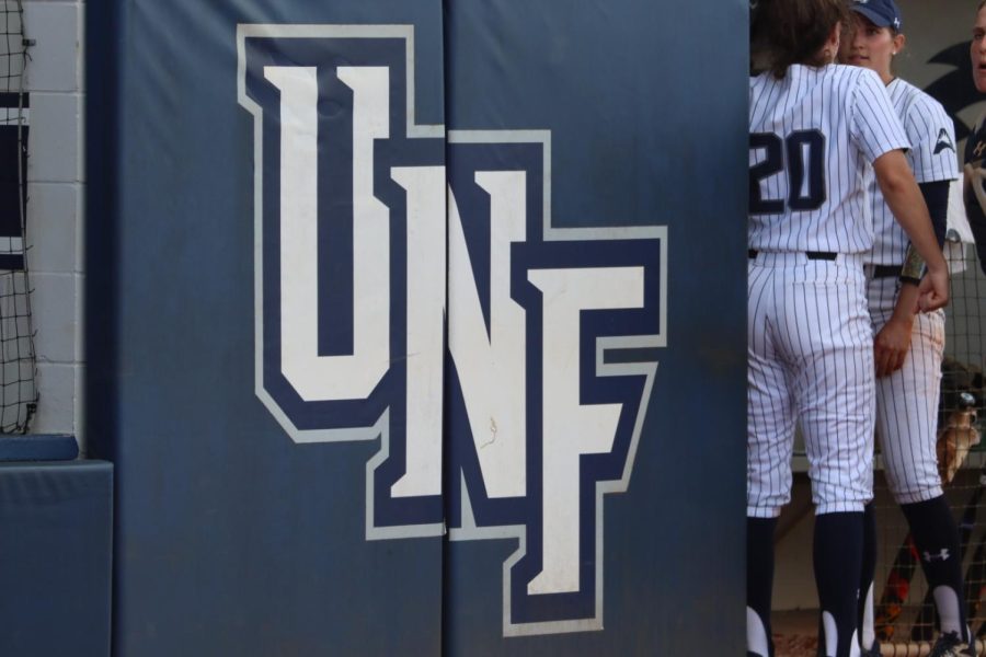 UNF softball players stand by dugout