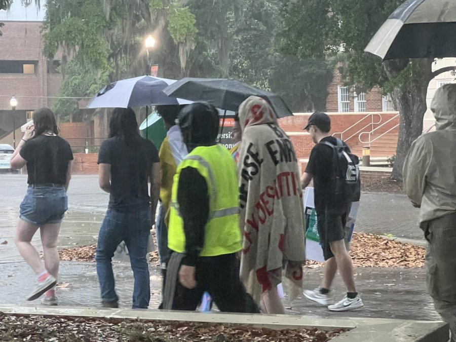 Protesters bundle beneath flags, umbrellas, rain coats or nothing as they leave FAMU's campus after the rally.