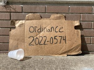 Ordinance 2022-0574, the name of the newly passed panhandling bill in Jacksonville, written on a piece of cardboard.