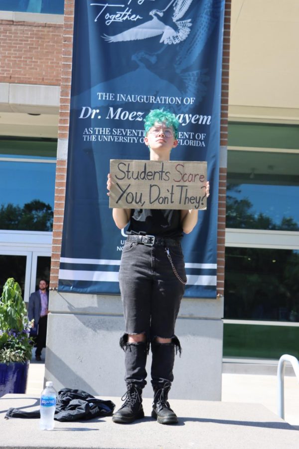 Icarus Olsen, a member of Students for a Democratic Society, holds a homemade sign in front of Lazzara Hall where University of North Florida President Moez Limayem would later be inaugurated.