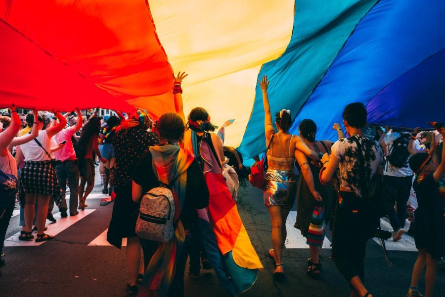 People walk beneath a giant rainbow flag.