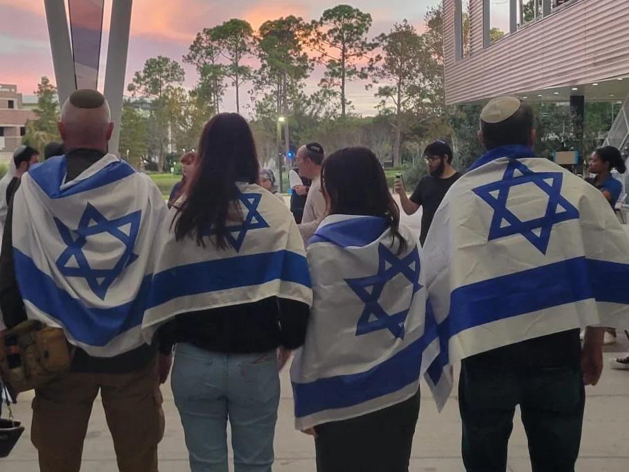 Members of the Jewish community wore the Israel flag on their shoulders at Monday night’s vigil. (Photo courtesy of the Chabad of UNF)
