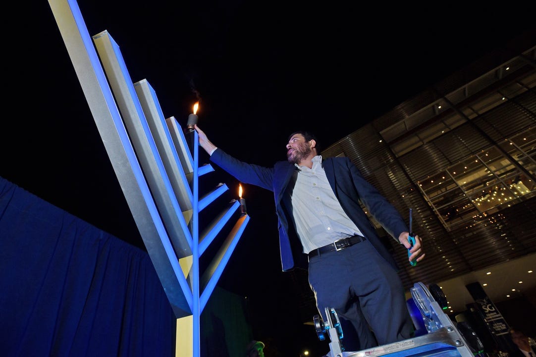 Rabbi Shmuli Novack lights the Menorah. (Photo courtesy of the Chabad at UNF)