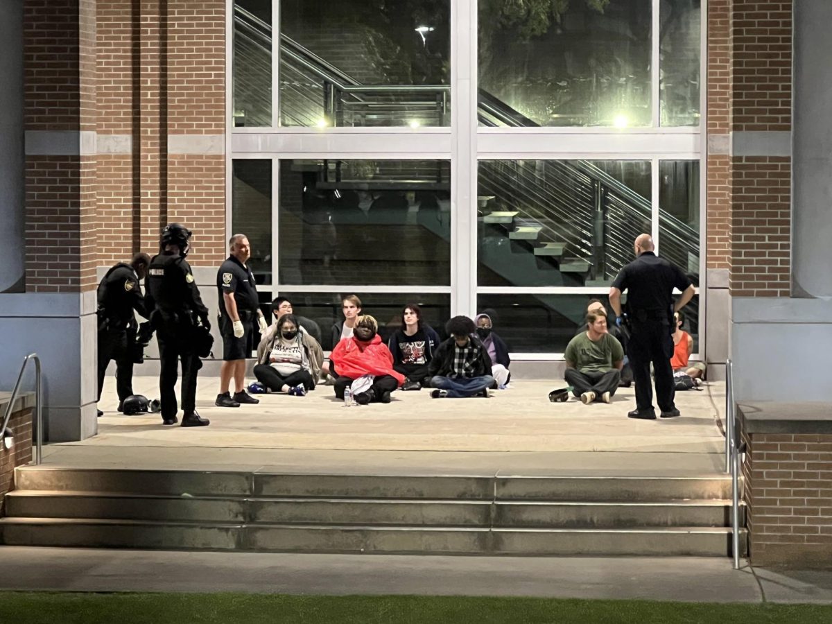 The protestors have been handcuffed and sat down in front of the Fine Arts Center.