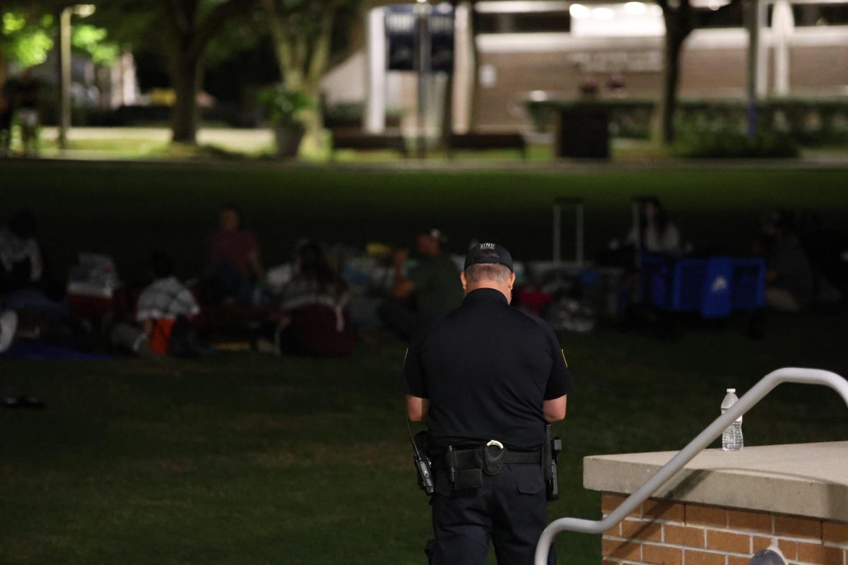 An officer puts on blue gloves as protesters stay on the Green. 