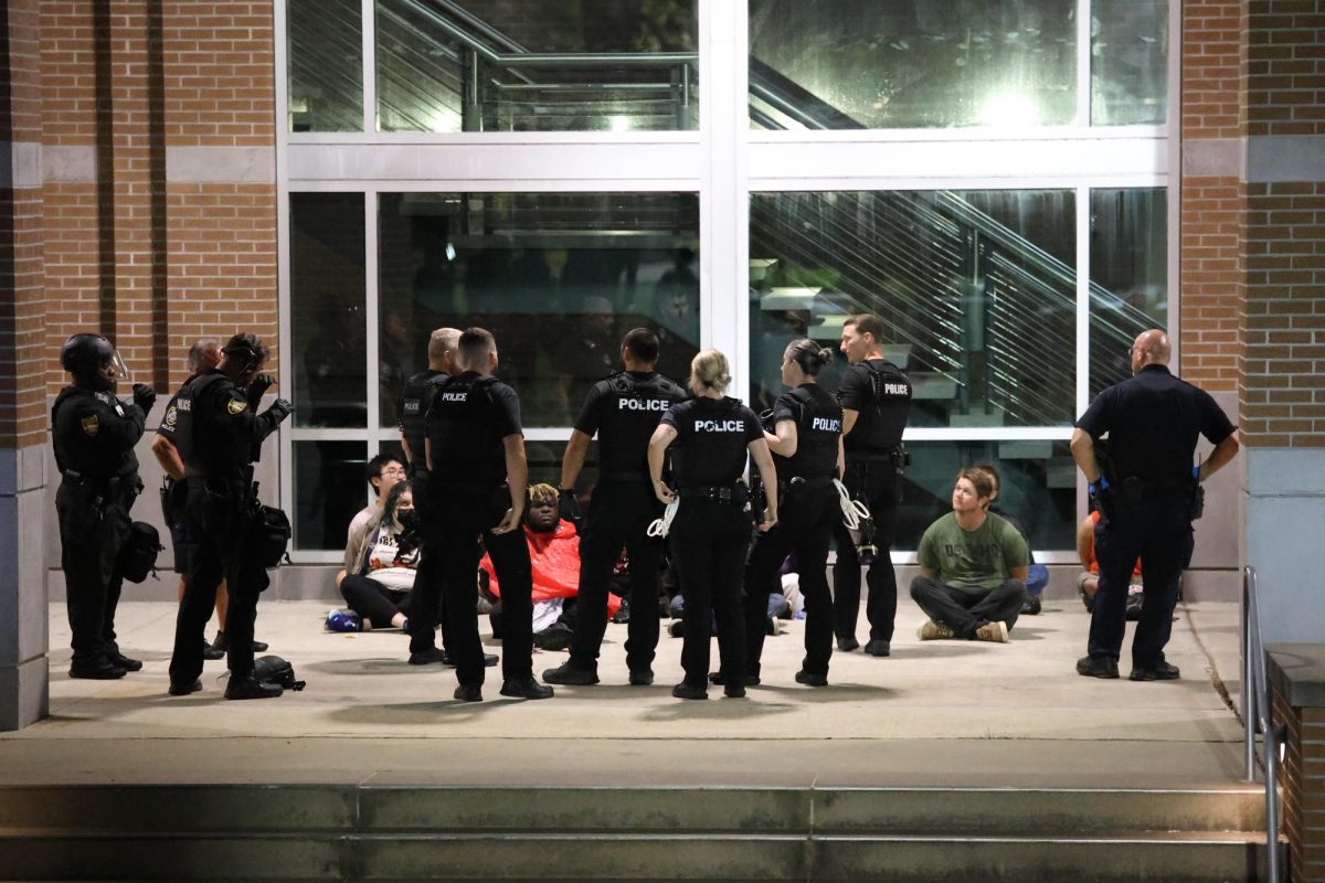 Officers stand as protesters sit in custody. 