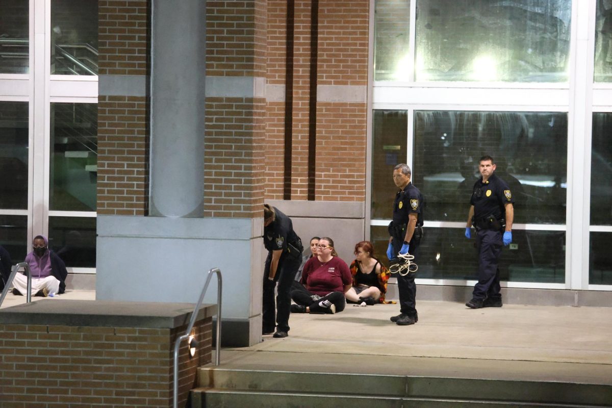 Protesters sit in zip cuffs along the Fine Arts Center on Thursday.