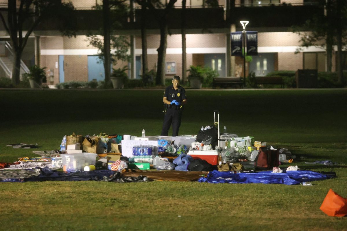 A university police officer stands over the water, snacks and other supplies left after protesters were arrested.
