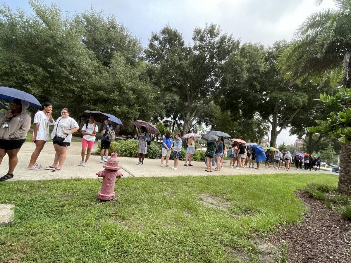 Students were waiting in line for the doors to open, holding umbrellas.