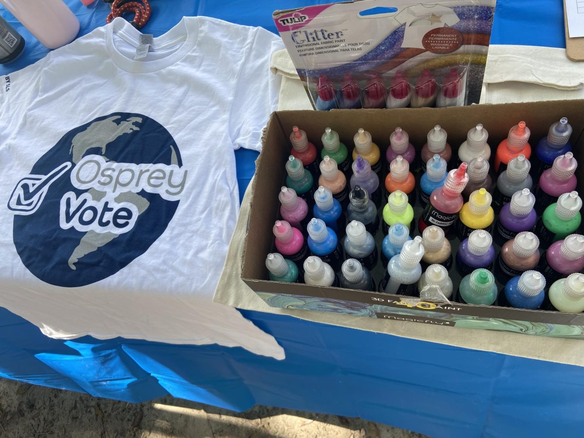 The Office of Student Learning and Civic Engagement booth provided numerous puffy paint and glitter colors for students to decorate tote bags. On the left, students could grab a free Osprey Vote T-shirt. 