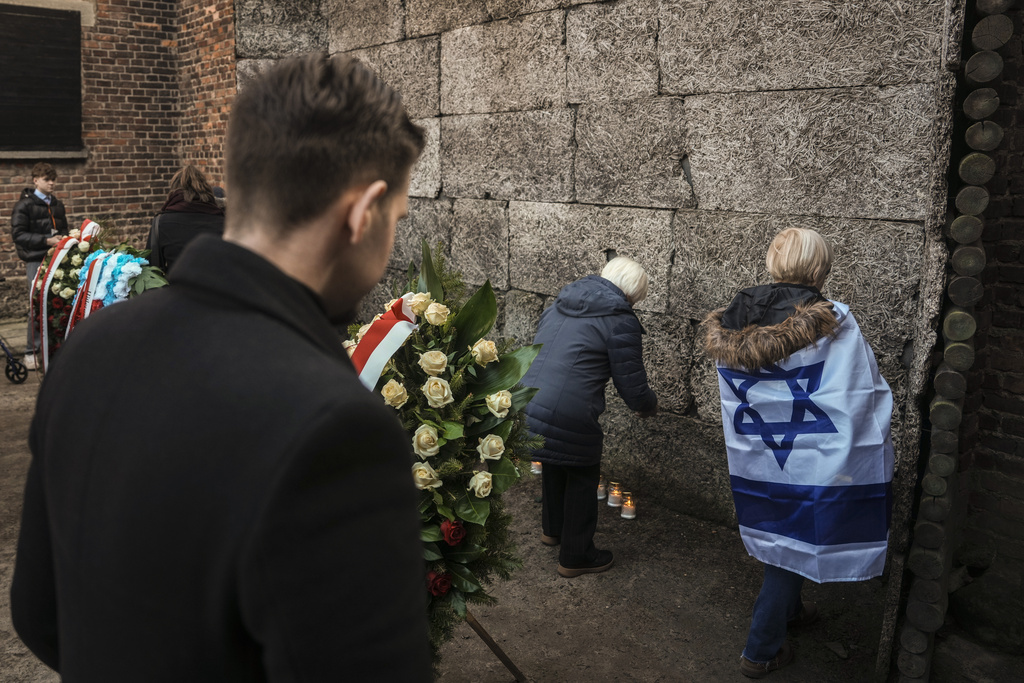 Survivors and relatives place candles near the Death Wall during a ceremony at the Auschwitz-Birkenau former Nazi German concentration and extermination camp, in Oswiecim, Poland, Monday, Jan. 27. 2025. (AP Photo/Oded Balilty)