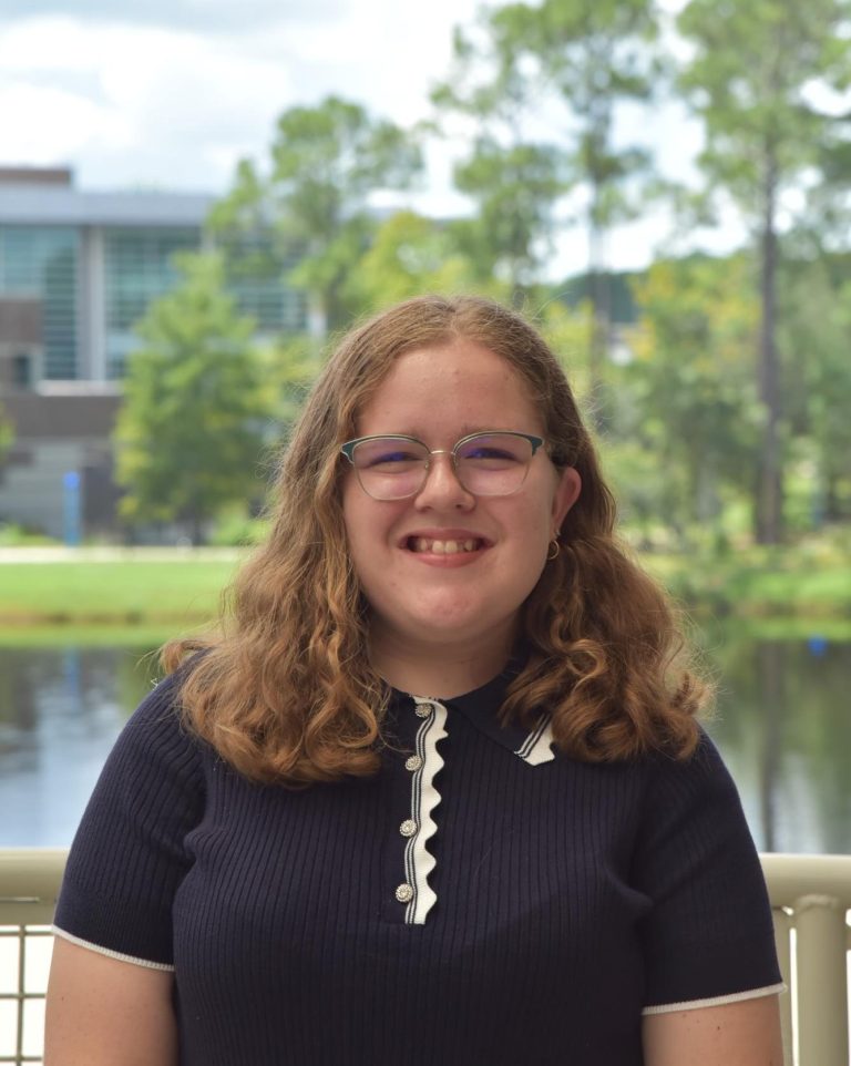Madeline is smiling wearing a dark blue shirt with white buttons