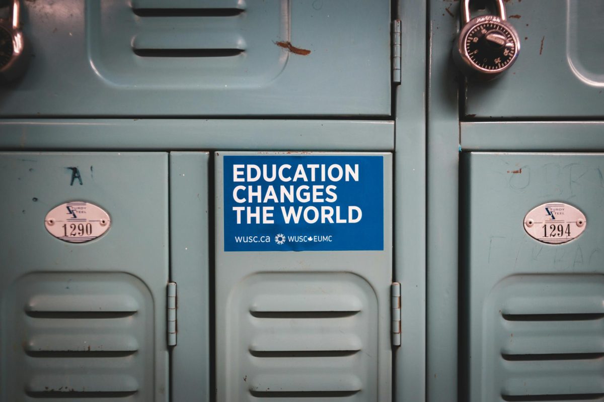 A grey school locker with a blue sticker on the top of it that reads "Education Changes the World" in large, white letters.