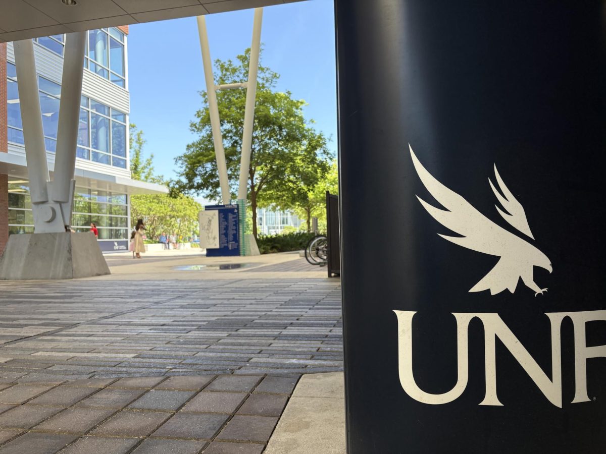 A white UNF logo on a dark blue column at the student union.