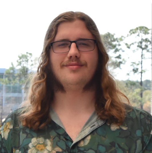 Jack smiling with long, light brown hair in a green button-up