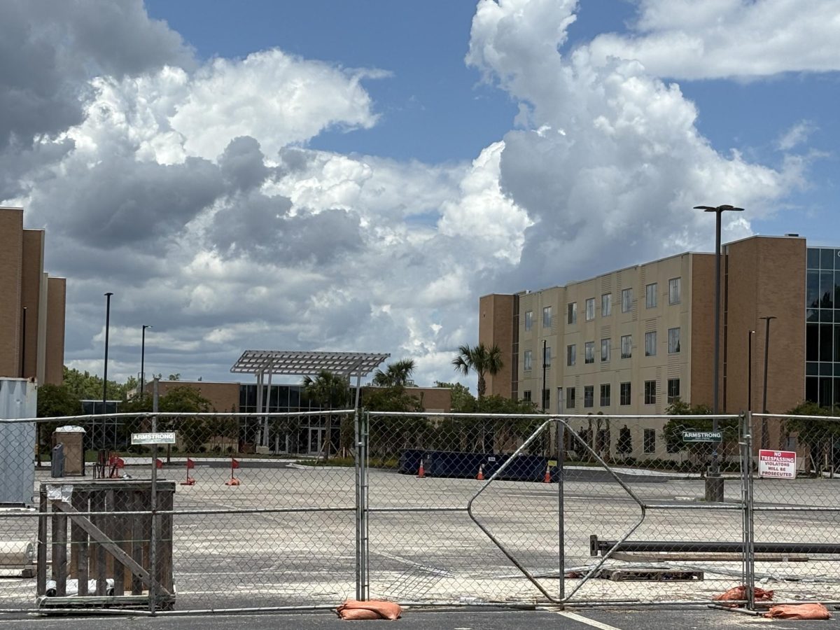 Construction site of tall brown Osprey Ridge dorm buildings, blocked off by a metal fence.