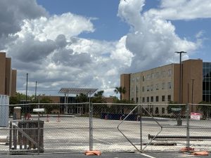 Construction site of tall brown Osprey Ridge dorm buildings, blocked off by a metal fence.