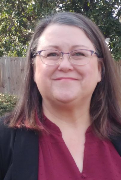 Dr. Kimberly Mayer is smiling with brown hair, glasses, wearing a black sweater and red blouse.