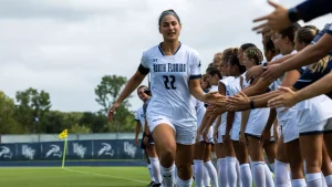 A soccer player wearing white high-fives their teammates while in a running motion.