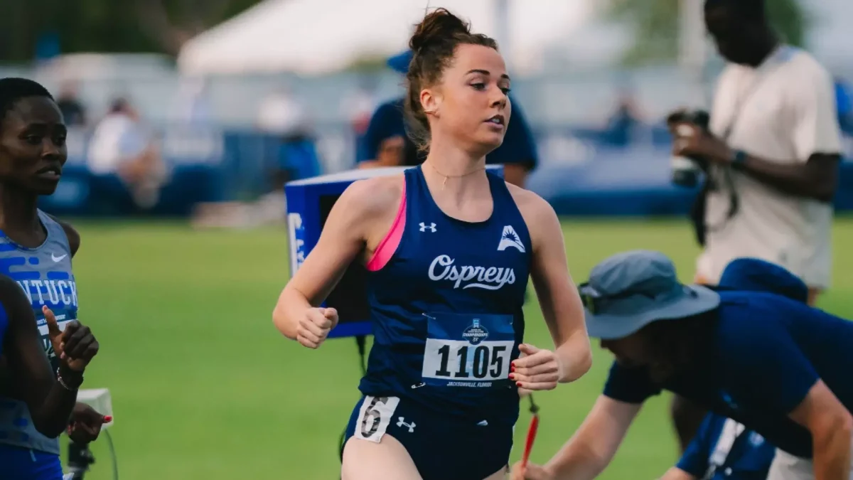 A track athlete is running wearing a dark blue uniform.