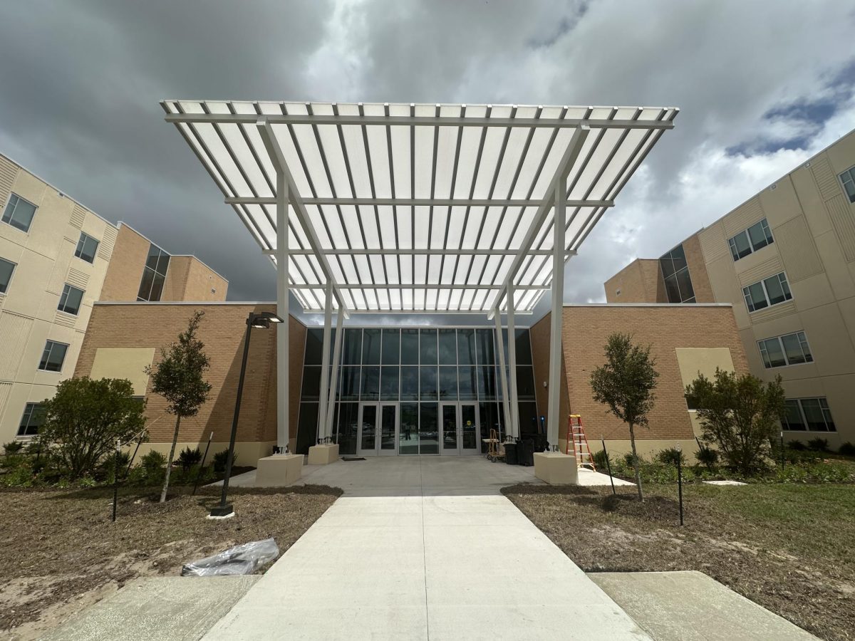 The front entrance of the honors dorms with a large meta overhang above the sidewalk.