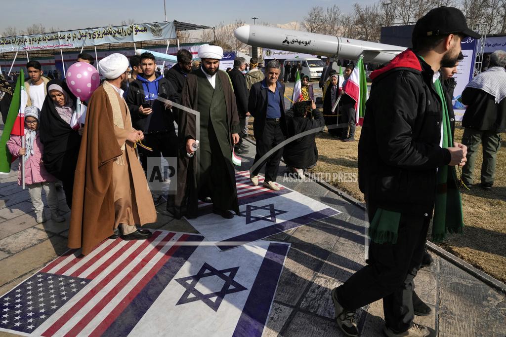 Demonstrators walk on representations of the Israeli and U.S. flags during their annual rally commemorating Iran's 1979 Islamic Revolution in Tehran, Iran. (AP Photo/Vahid Salemi)